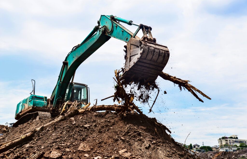 Excavator clearing debris from dirt mound