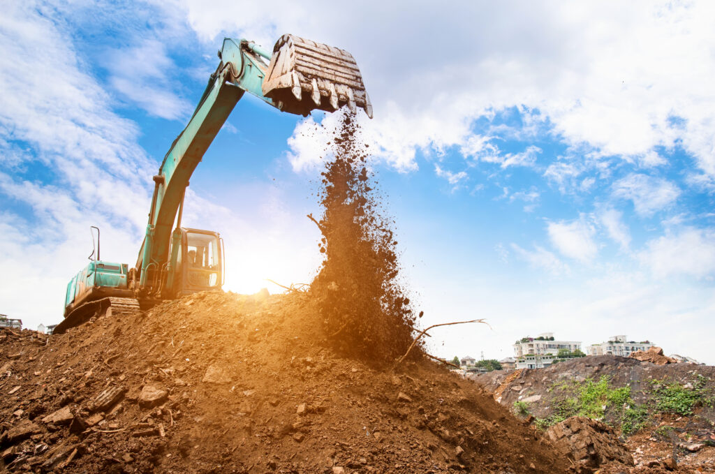 Excavator dumping soil under blue sky